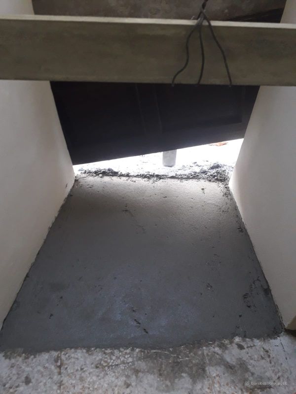 Realizzazione e livellamento del sottofondo cementizio in un ambiente interno durante i lavori di ristrutturazione.