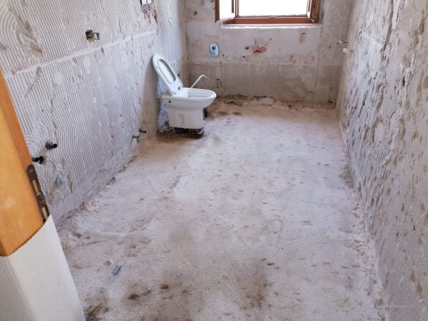 Bagno durante la fase di demolizione, con pavimenti e rivestimenti rimossi per la successiva ristrutturazione.